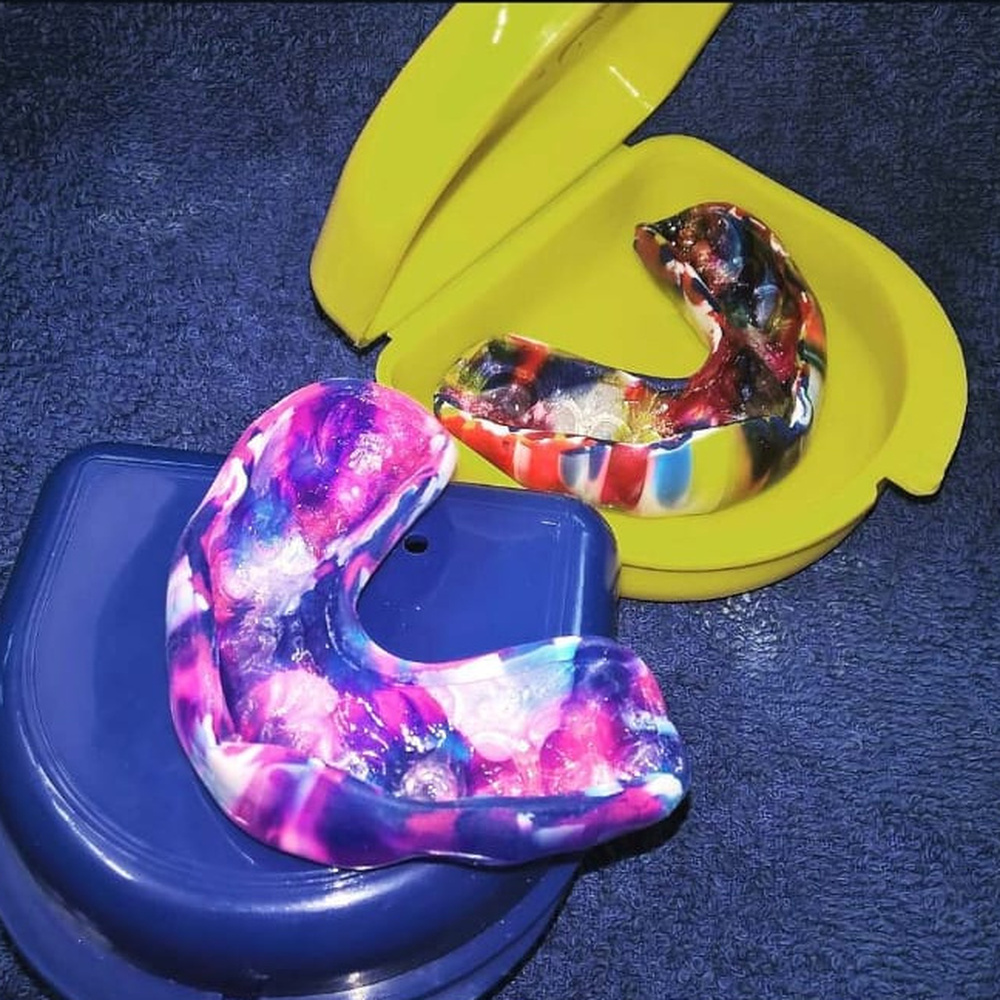 Two custom multicoloured gum guards in protective cases